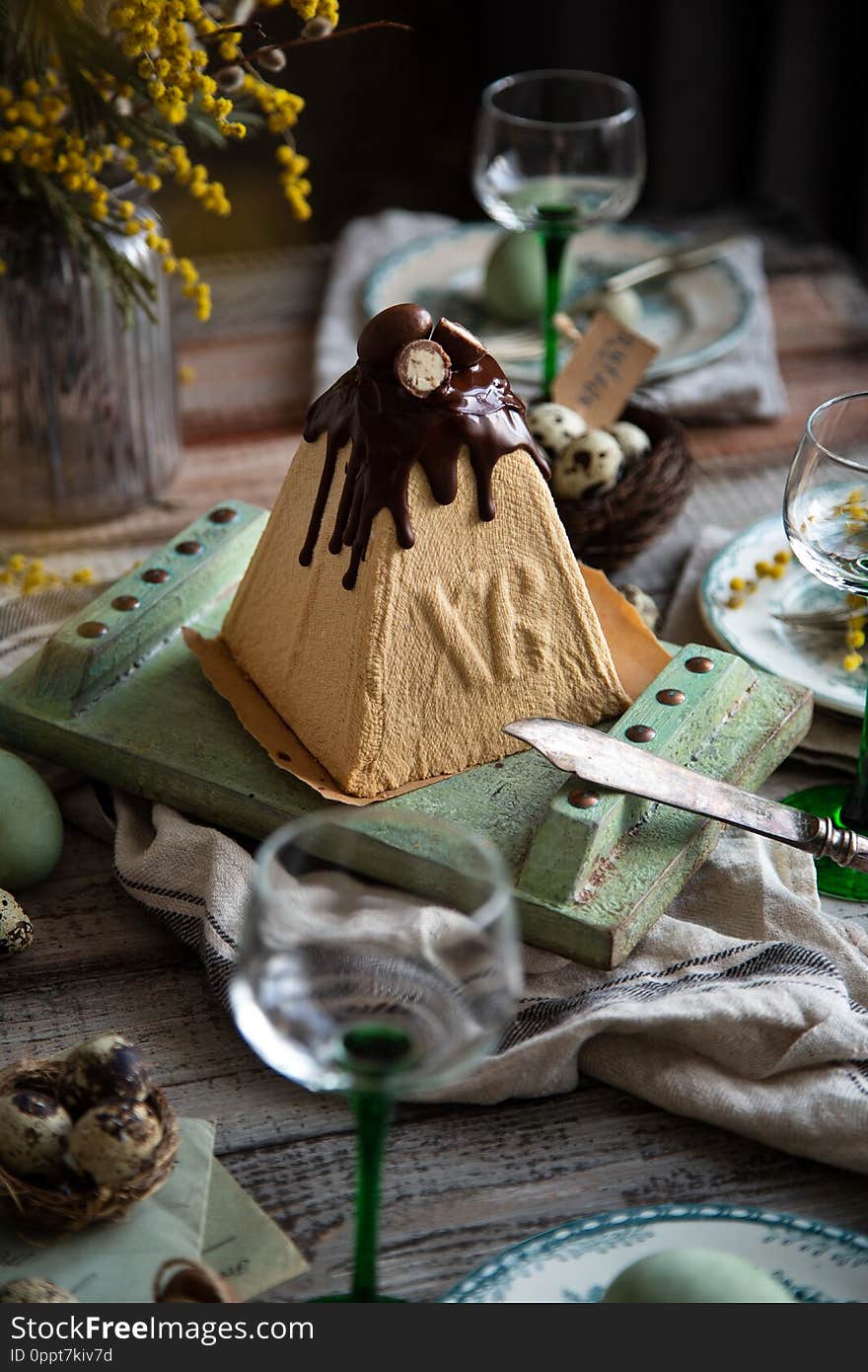 Orthodox Easter table setting with caramel easter cottage cheese cake on wooden light green board on grey wooden table