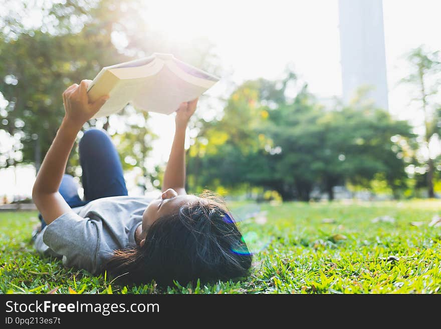 Asian teenage girls are lying reading a books on the grass in the park. Asian teenage girls are lying reading a books on the grass in the park