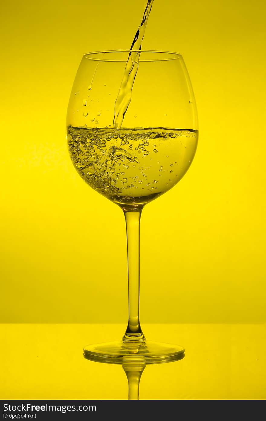 Full wine glass on yellow background, full wineglass on green light