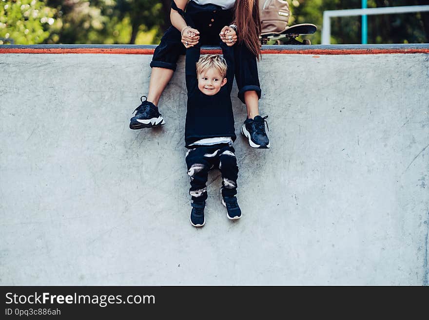 Beautiful young hipster mom holds her little son by the hands