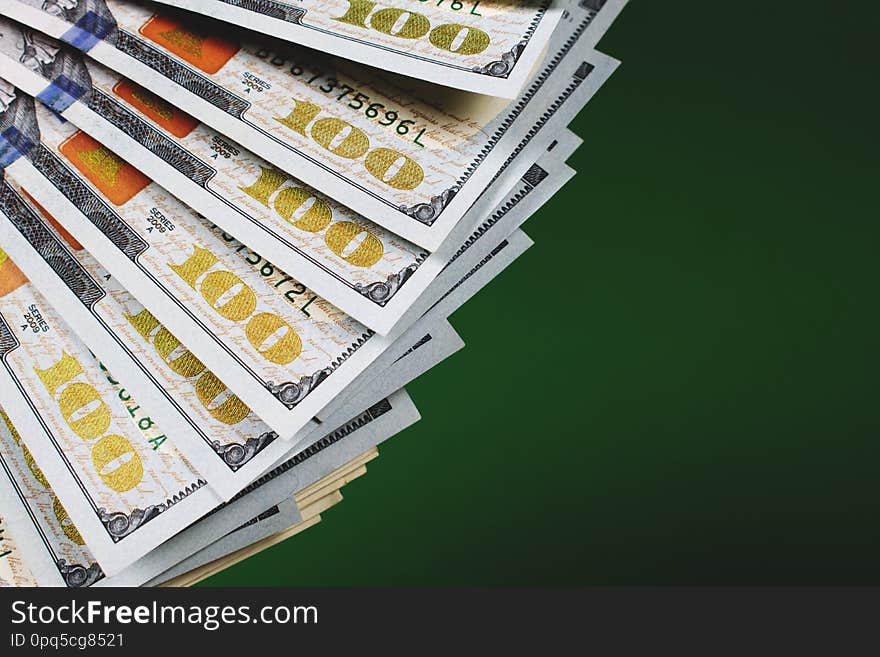 Fan of one hundred dollar banknotes on a green background with copy space for text. Budgeting, finance and saving concept. Fan of one hundred dollar banknotes on a green background with copy space for text. Budgeting, finance and saving concept