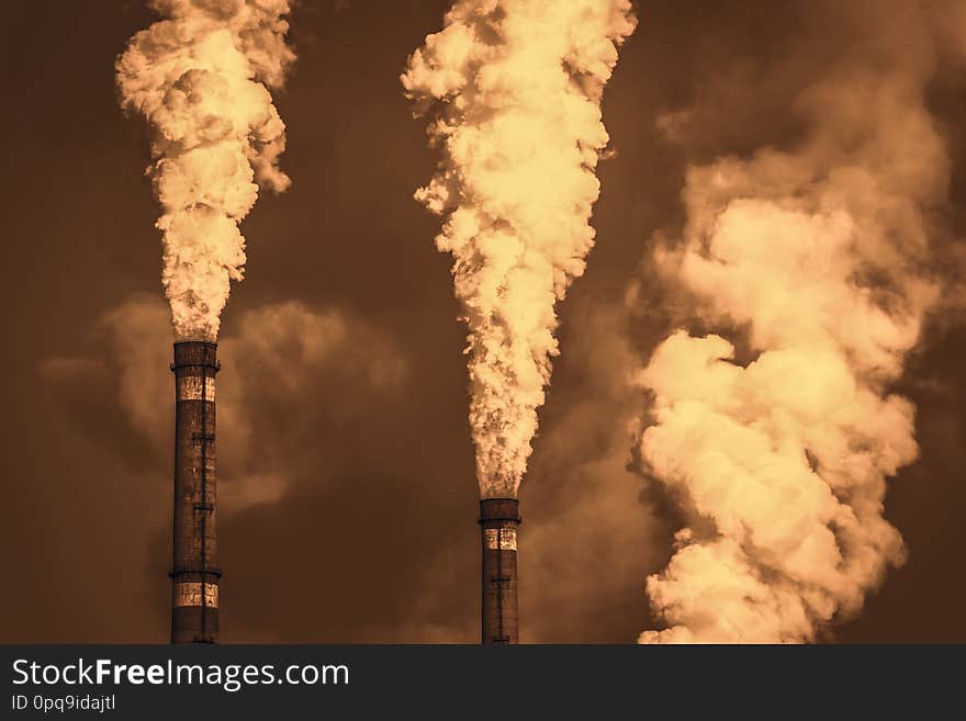 The thick smoke rises high from the industrial pipes. Pollution of the environment with waste products. The thick smoke rises high from the industrial pipes. Pollution of the environment with waste products