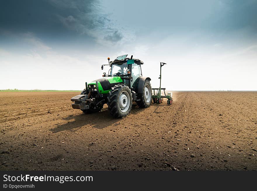 Farmer with tractor seeding sowing crops at agricultural field