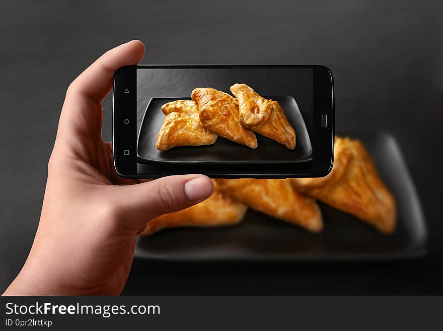 Hands of a man takes photos of food on the table with the phone. Fresh buns with vegetable filling. Wheat bread filling on a dark background. Photos of the smartphone for the post in social networks