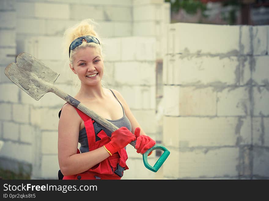 Woman worker using shovel standing on industrial construction site, working hard on house renovation. Woman worker using shovel standing on industrial construction site, working hard on house renovation