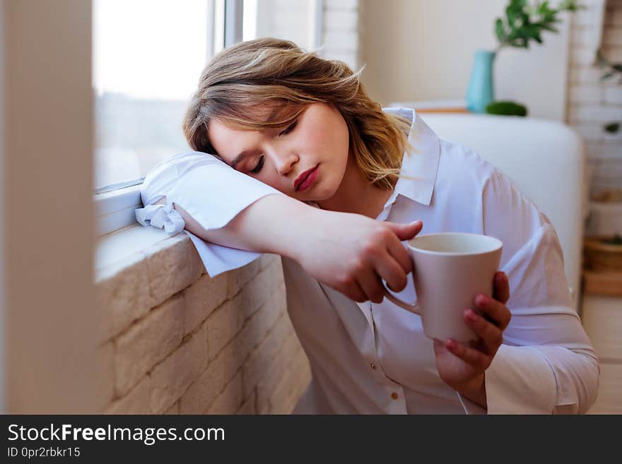 So tired. Nice tired woman falling asleep while holding a cup of tea in her hands. So tired. Nice tired woman falling asleep while holding a cup of tea in her hands