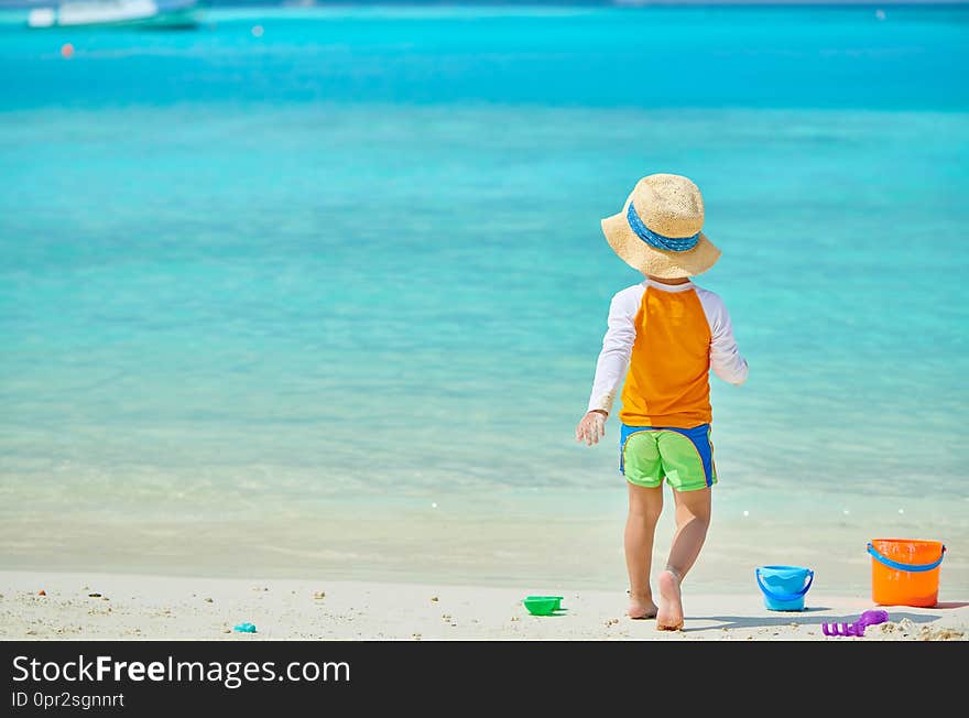 Three year old toddler boy playing with beach toys on beach. Summer family vacation at Maldives. Three year old toddler boy playing with beach toys on beach. Summer family vacation at Maldives