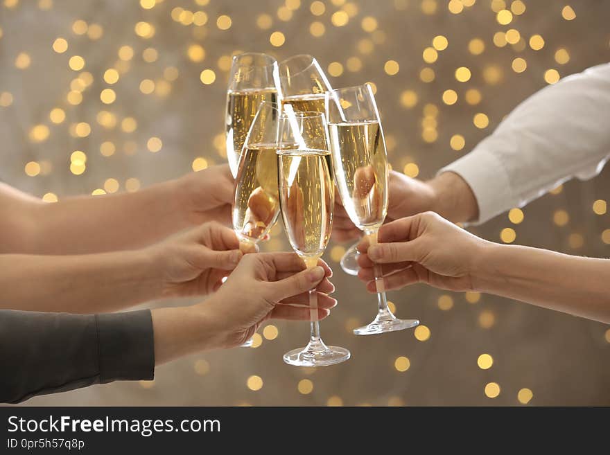 People clinking glasses of champagne on blurred background, closeup