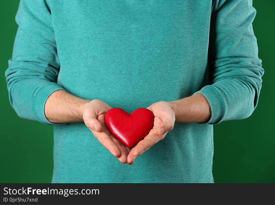 Man holding decorative heart on color background