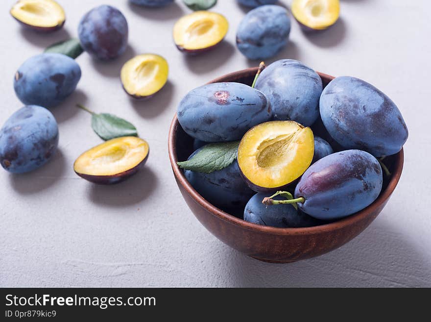 Fresh plums in bowl on wooden table . Fruit background