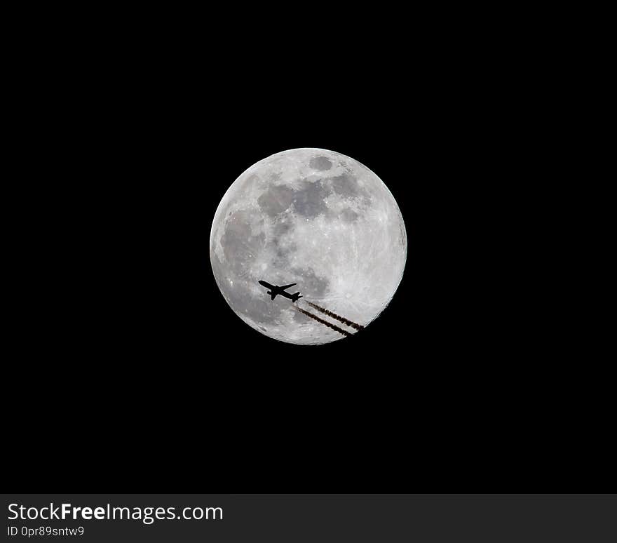 A commercial airliner at high altitude is silhouetted as it passes in front of a full moon at night 2 of 3. A commercial airliner at high altitude is silhouetted as it passes in front of a full moon at night 2 of 3