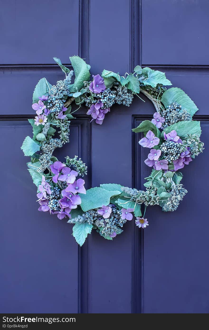 Close-up of beautiful green and purple wreath on deep purple wooden door