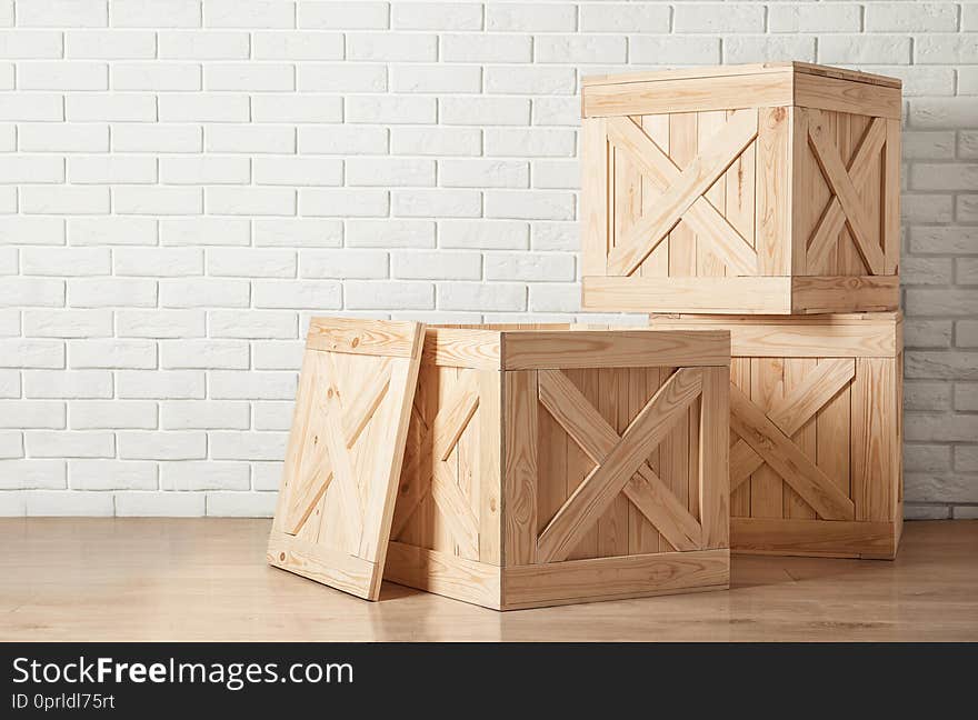 Wooden crates on floor near brick wall, space for text