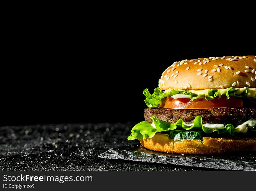 Burger with juicy beef,tomatoes and salad. On rustic background