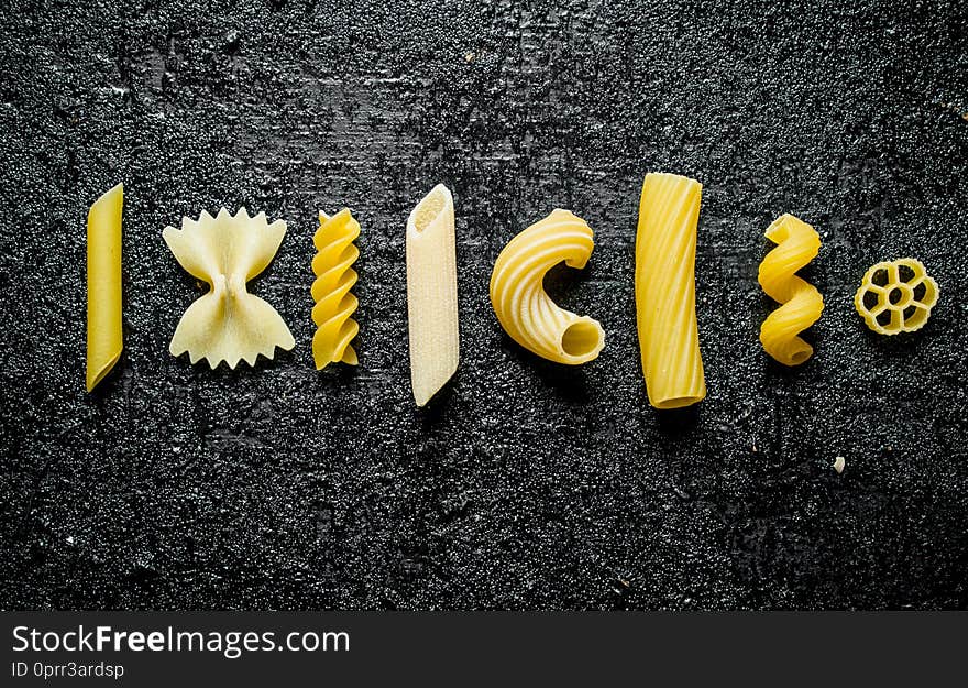 Different types of dry pasta. On black rustic background