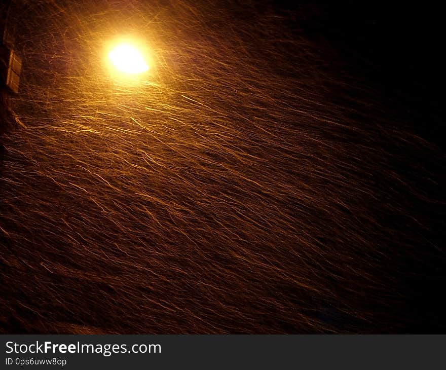 Night snowstorm illuminated by yellow light of the lantern, visible trails from flying snowflakes. Night snowstorm illuminated by yellow light of the lantern, visible trails from flying snowflakes