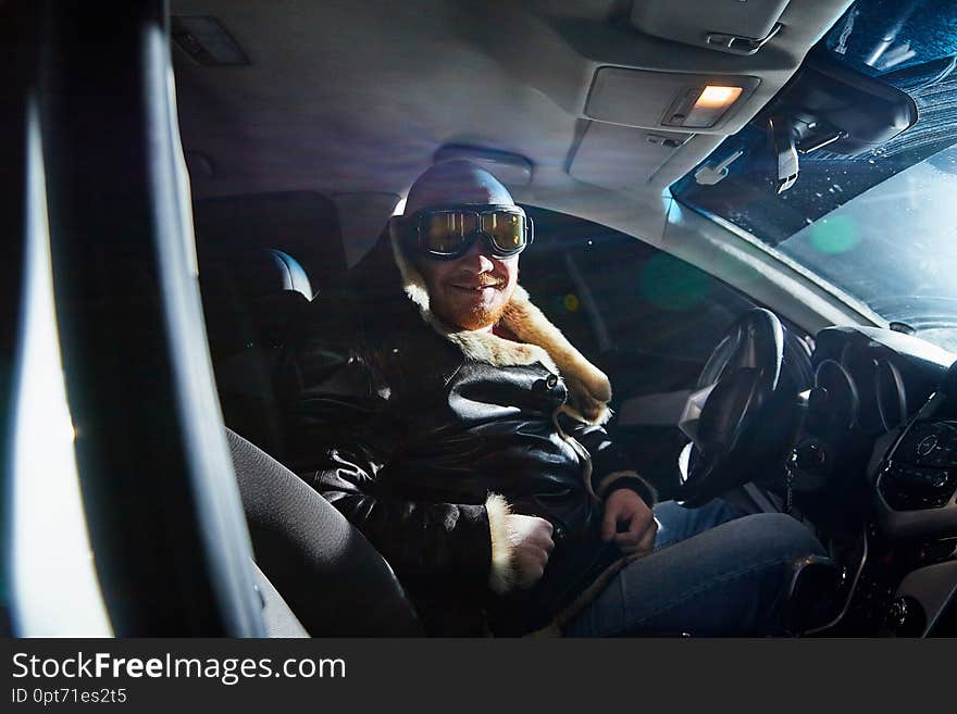 Funny male driver in a leather jacket in the car in the dark. Drunk driver in the car. Night unusual photo shoot. Funny male driver in a leather jacket in the car in the dark. Drunk driver in the car. Night unusual photo shoot