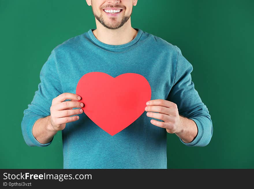 Man with decorative heart on color background, closeup