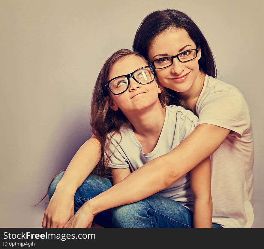 Happy relaxed casual mother and smiling kid in fashion glasses hugging on purple background with empty copy space wall background. Vintage toned portrait. Happy relaxed casual mother and smiling kid in fashion glasses hugging on purple background with empty copy space wall background. Vintage toned portrait