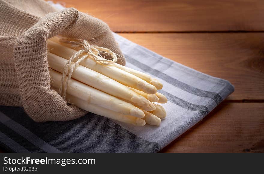 Freshly harvested asparagus in a jute bag on a wooden cutting board