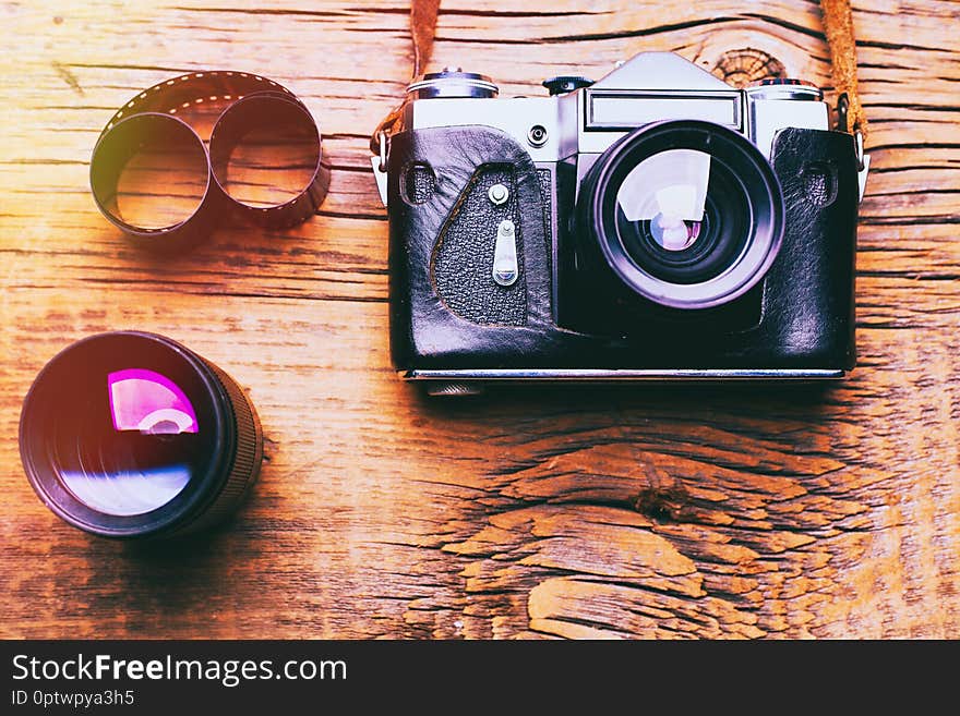 Old retro camera on vintage wooden boards abstract background, close up photo of old camera lens over wooden table, image is retro filtered, selective focus