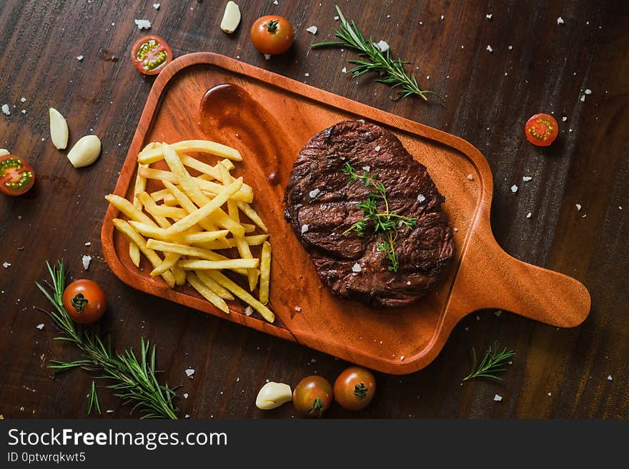 Grilled kebab grilled meat steak lies with french frieson a Rustic old elegant wooden cutlery cutting chopping board chili, with tomatoes, sauce, dill onions, on the table on top, side, bottom shot