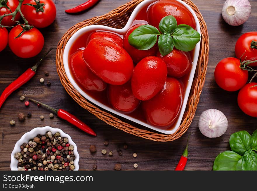 Whole canned tomatoes in their own juice with spices on a dark wooden background. Selective focus