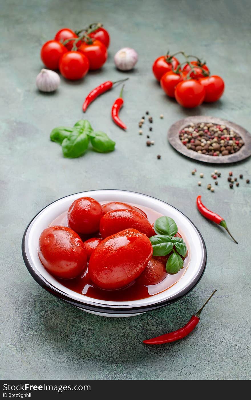 Whole canned tomatoes in their own juice with spices on a green slate background. Selective focus