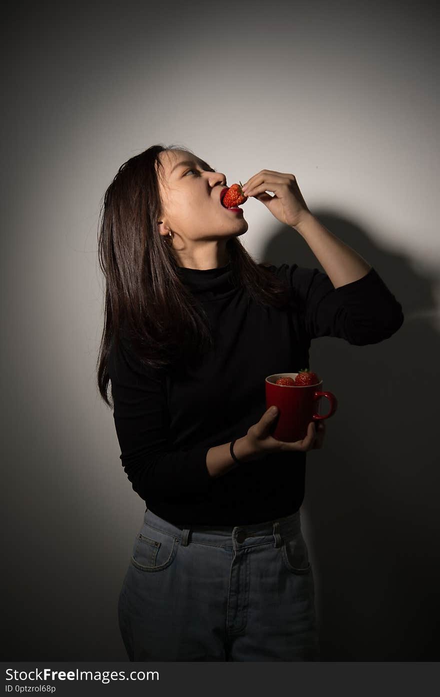 Studio shot of a beautiful asian girl eating fresh strawberries. Studio shot of a beautiful asian girl eating fresh strawberries