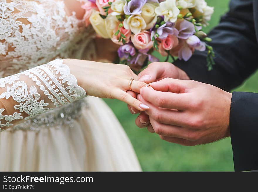 Groom wears a ring on the hand of the bride on wedding ceremony outdoor