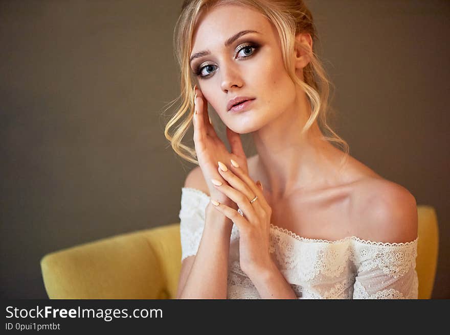 Portrait of a beautiful miniature bride in a lace dress. Hair with curls. Emphasis in make-up on the eyes.Blonde.