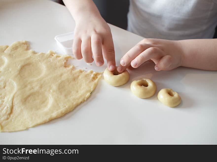 The child makes cookie molds on a white table. Preparation of homemade dessert. close up