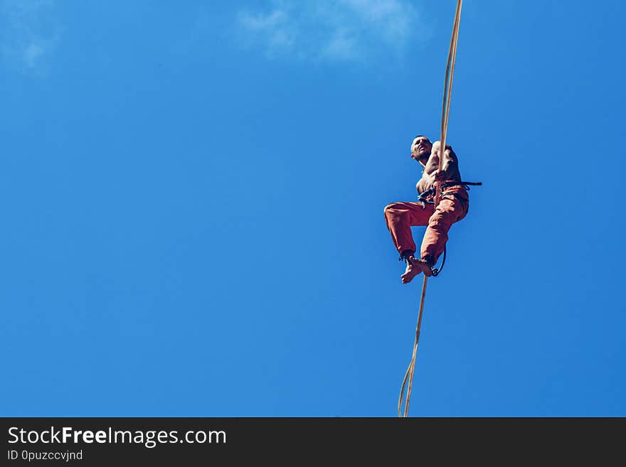 Man walking along high line rope on the blue sky background. Man walking along high line rope on the blue sky background