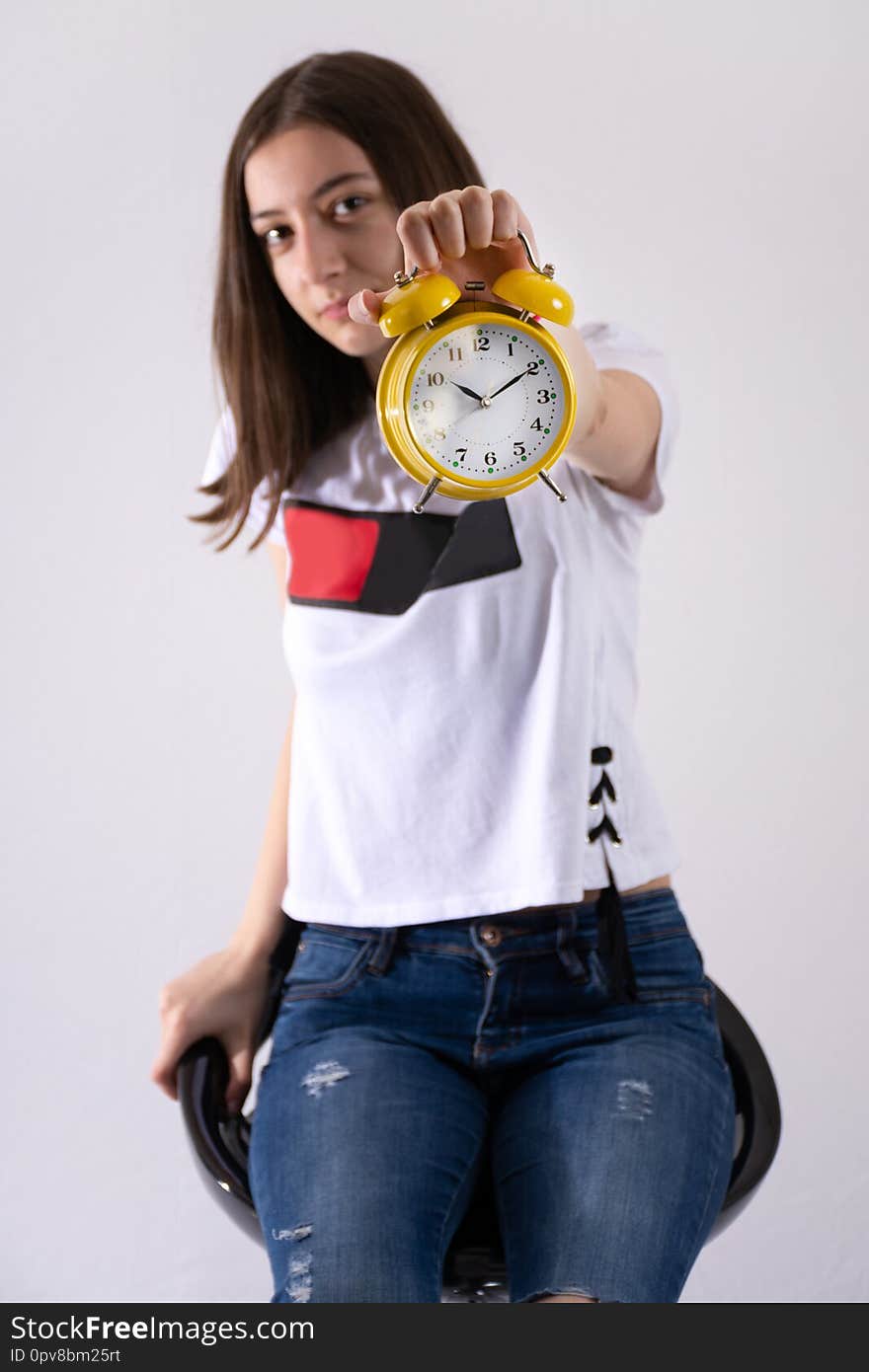 Young girl with retro clock in hand showing time on yellow clock isolated on white background