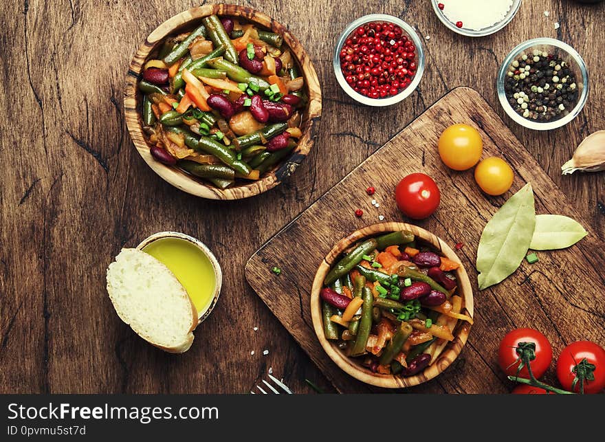 Green beans with vegetables, mushrooms and tomatoes. Food cooking background, vintage wooden rustic table. Copy space,  top view