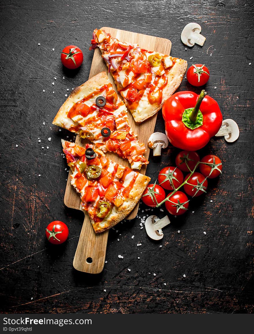 Slices of Mexican pizza with bell peppers and tomatoes. On dark rustic background