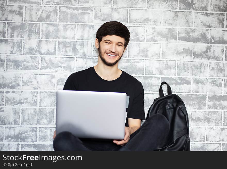 Young man smiling with laptop in his hands.