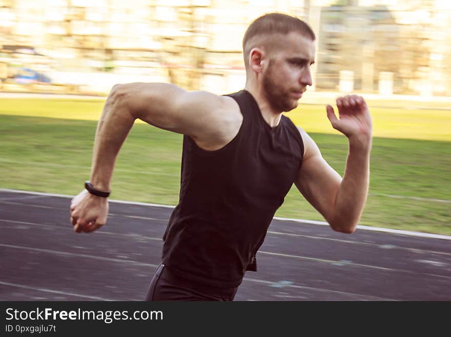 One caucasian male is doing a sprint start. running on the stadium on a rubber track. Track and field runner in sport uniform.