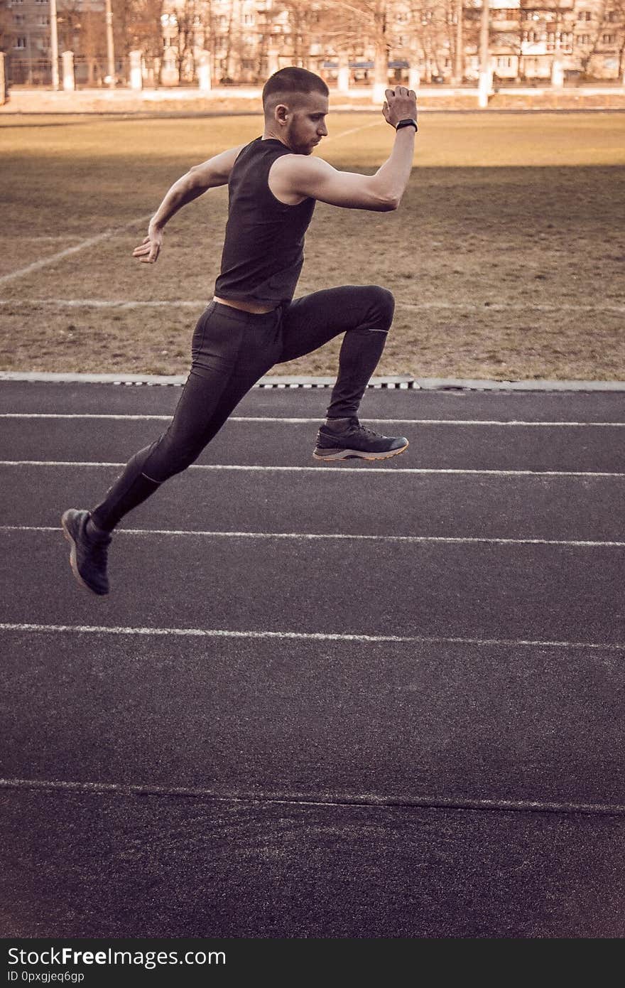 One caucasian male is doing a sprint start. running on the rubber track. Track and field runner in sport uniform. energetic physical activities. outdoor exercise, healthy lifestyle. running jumps