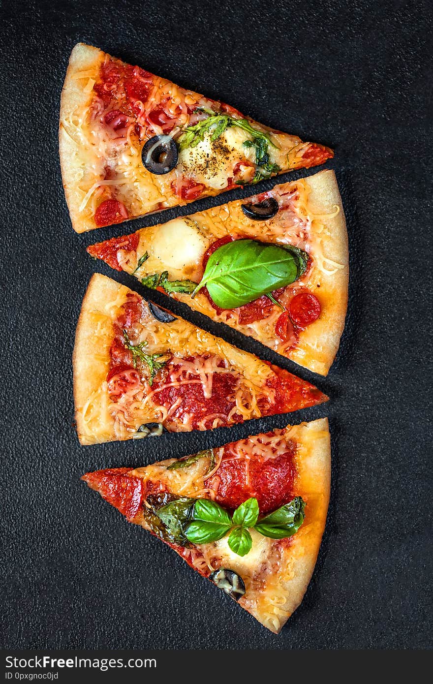 Slices of pizza with  pepperoni and basil leaf  with spices on black background, copy space. Flatbread pizza. Top view..
