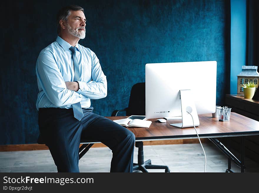 Concentrated at work. Focused mature businessman working and taking notes in his modern office.