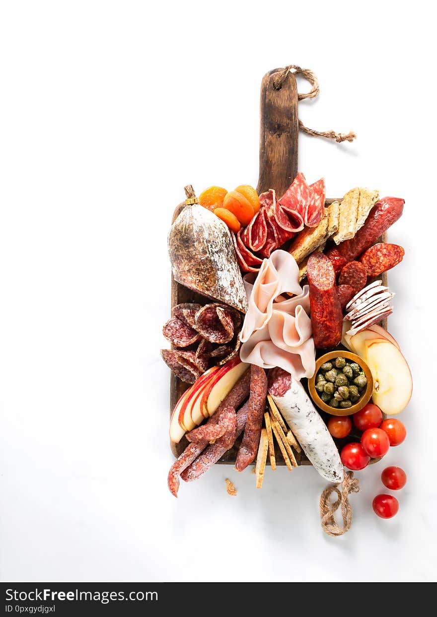 Cold meat plate, charcuterie on white background with copy space. Traditional Spanish tapas selection - chorizo, salchichon, jamon serrano, lomo, salami. Top view