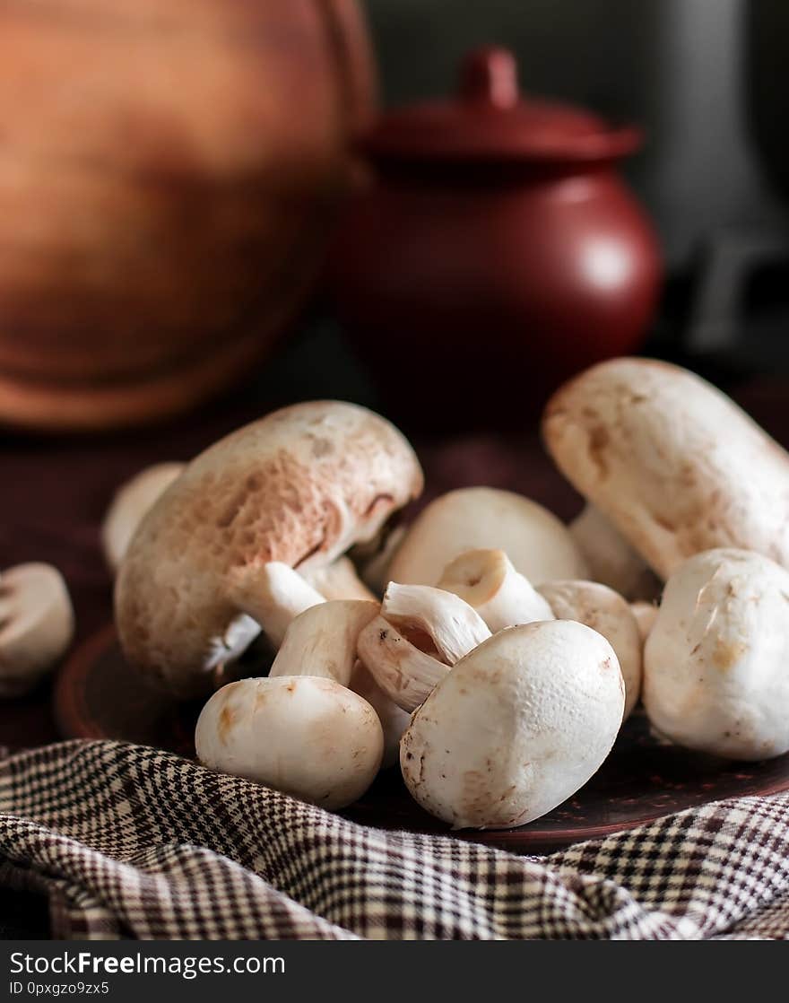 Fresh champignon mushrooms group on the table. Fresh vegetables mushrooms - the concept of healthy proper nutrition. Dark Food