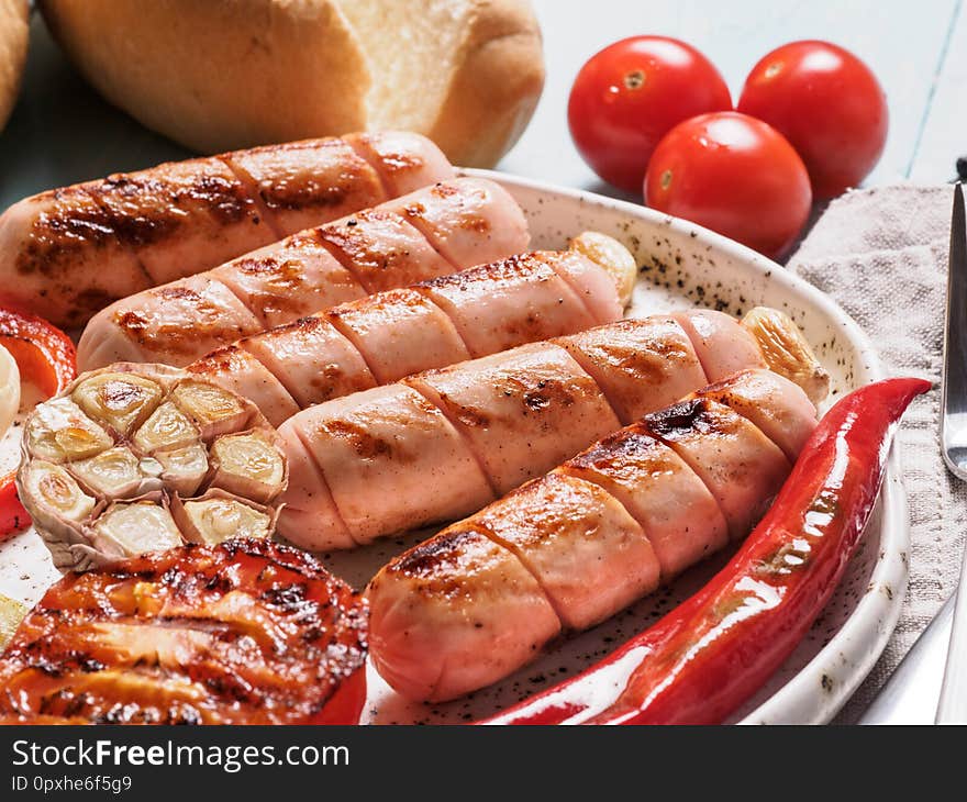 Close up view of chicken homemade sausages with buns bread. Grilled sausages and grilled vegetables in craft trendy plate. Home hotdogs. Close up view of chicken homemade sausages with buns bread. Grilled sausages and grilled vegetables in craft trendy plate. Home hotdogs.