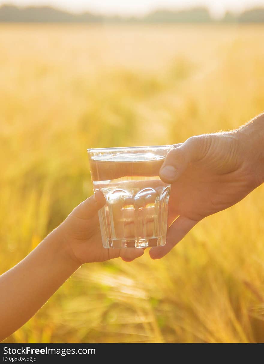 The father gives the child a glass of water. Selective focus. nature