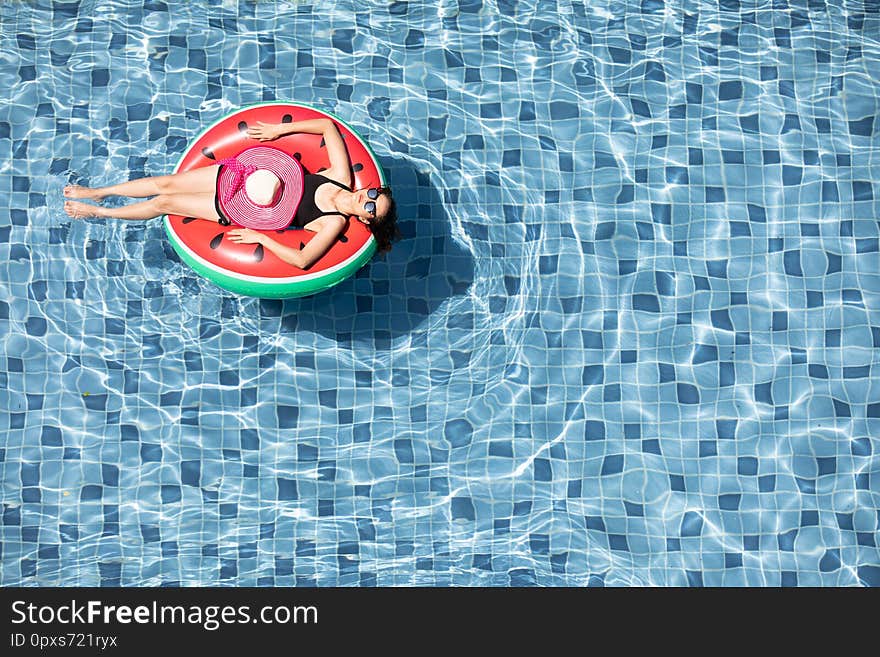 Top view shot woman wear sunglasses laying on balloon in blue water swimming pool with copy space, concept for luxury and happy lifestyle. Top view shot woman wear sunglasses laying on balloon in blue water swimming pool with copy space, concept for luxury and happy lifestyle