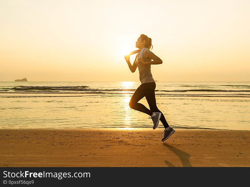 Woman running on beach at sunrise