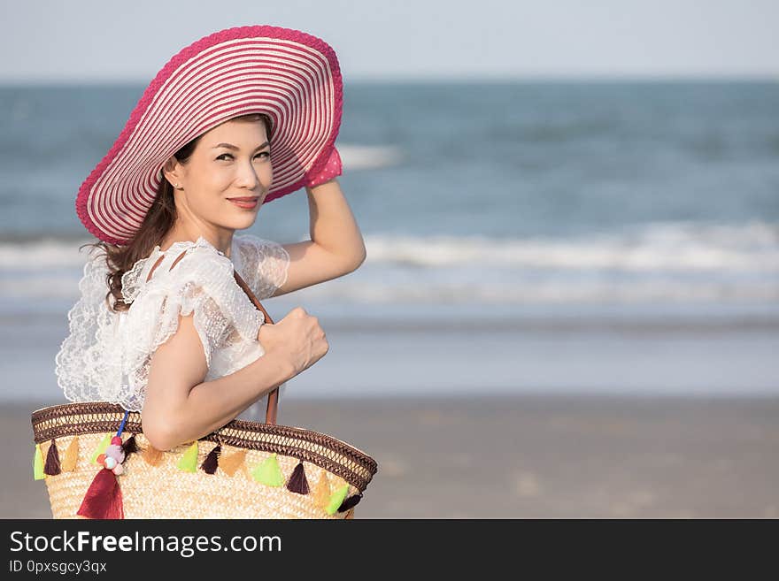 Woman wearing hat and holding bag on beach