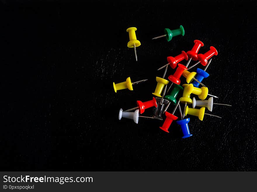 Top view of colorful thumbtacks on a black background. Top view of colorful thumbtacks on a black background