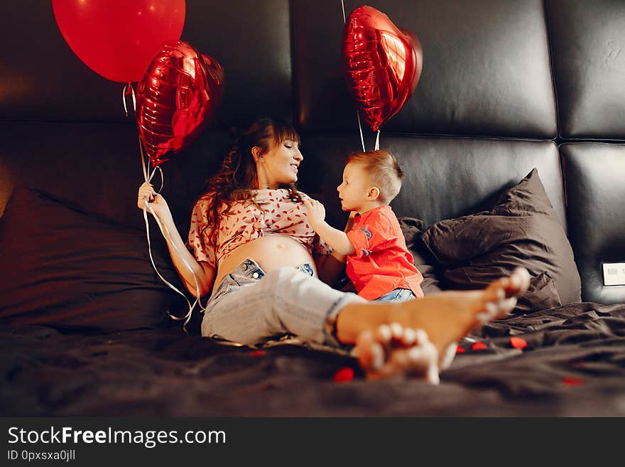 Pregnant women at home. Mother with son in a bed. Family in a room with decorstions for Valentine`s day. Pregnant women at home. Mother with son in a bed. Family in a room with decorstions for Valentine`s day